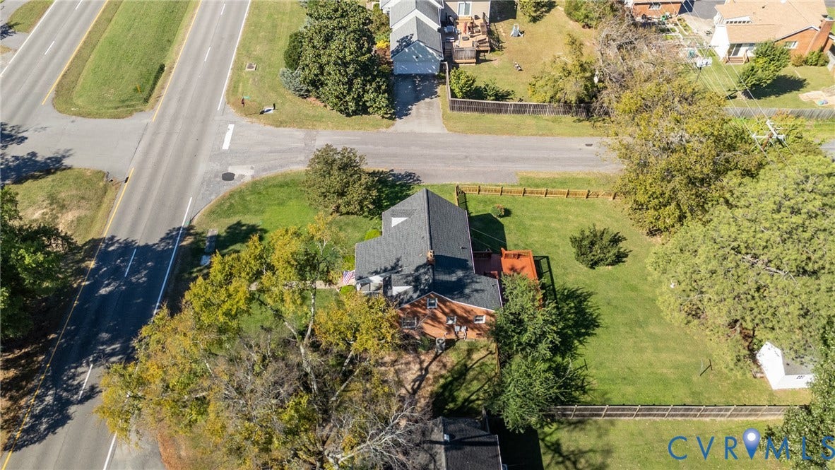 6614 Monument Avenue, Westhaven, Henrico, VA 23226 Aerial view of a brick exterior residence featuring a dark shingle roof, an elevated wooden deck, and a fenced yard with mature trees
