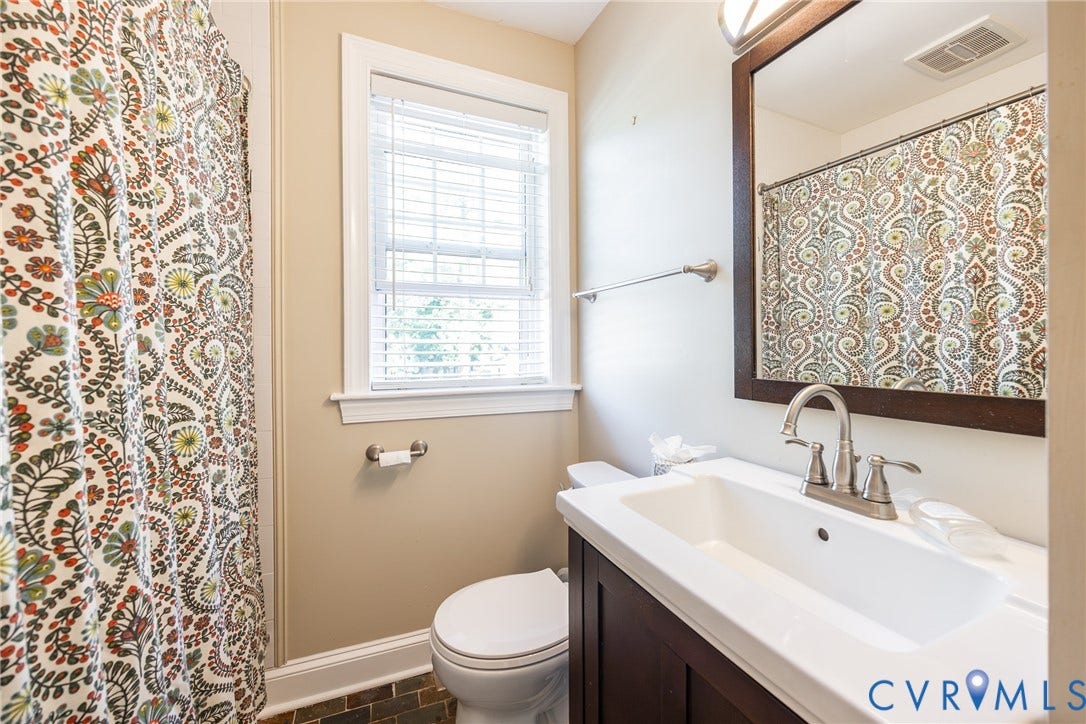 6614 Monument Avenue, Westhaven, Henrico, VA 23226 Bathroom featuring a dark wood vanity with a white integrated sink, high-arc brushed nickel faucet, framed wall mirror, and window with white slatted blinds