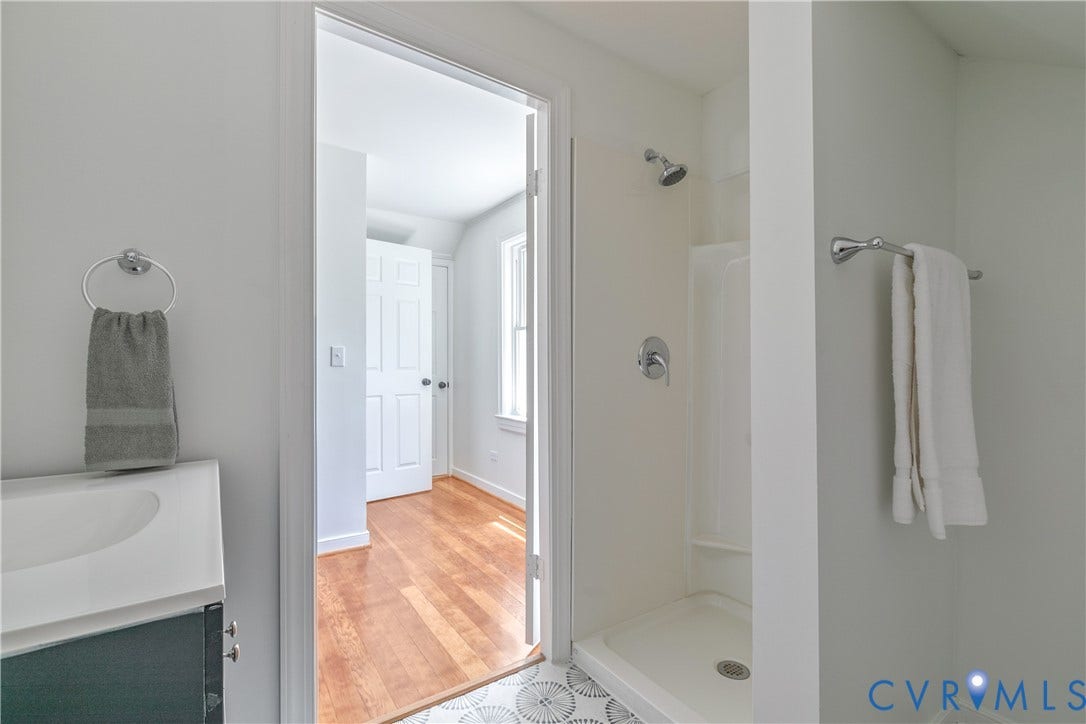 7263 Grace Lane, Mechanicsville, VA 23111 Compact bathroom featuring a shower with chrome fixtures, a patterned floor tile, and a vanity with a white countertop