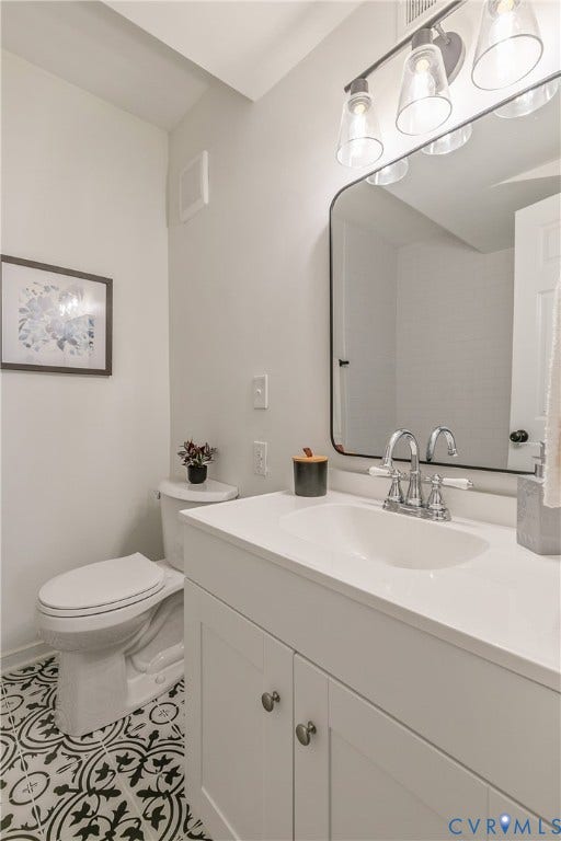 7263 Grace Lane, Mechanicsville, VA 23111 Bathroom featuring patterned floor tiles, a white vanity with panel cabinetry and silver-toned hardware, a white countertop with an integrated sink, a contemporary chrome faucet, and a rectangular mirror with a black frame