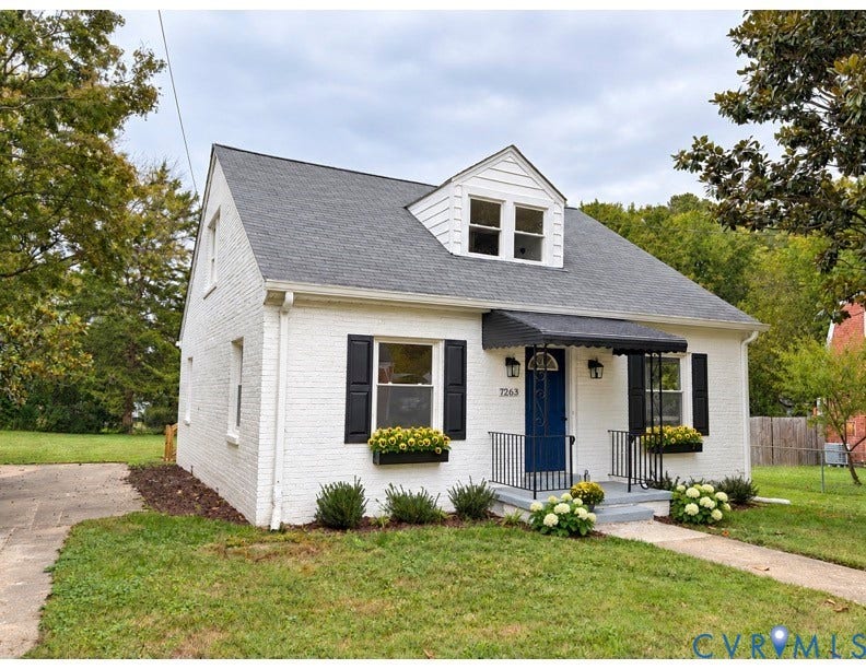 7263 Grace Lane, Mechanicsville, VA 23111 White brick exterior featuring a steep gabled roof, prominent front-facing dormer, contrasting black window shutters, and a metal door awning