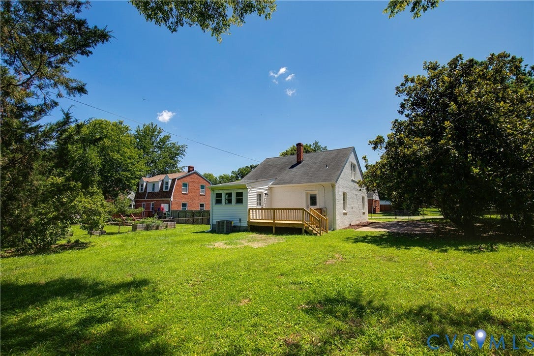 7263 Grace Lane, Mechanicsville, VA 23111 Expansive rear yard featuring a white-painted brick exterior, a newly constructed wood deck, a white sunroom addition, and mature perimeter trees