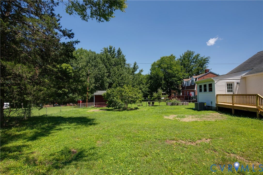 7263 Grace Lane, Mechanicsville, VA 23111 Expansive green lawn with mature trees, a wooden deck, and a detached red shed