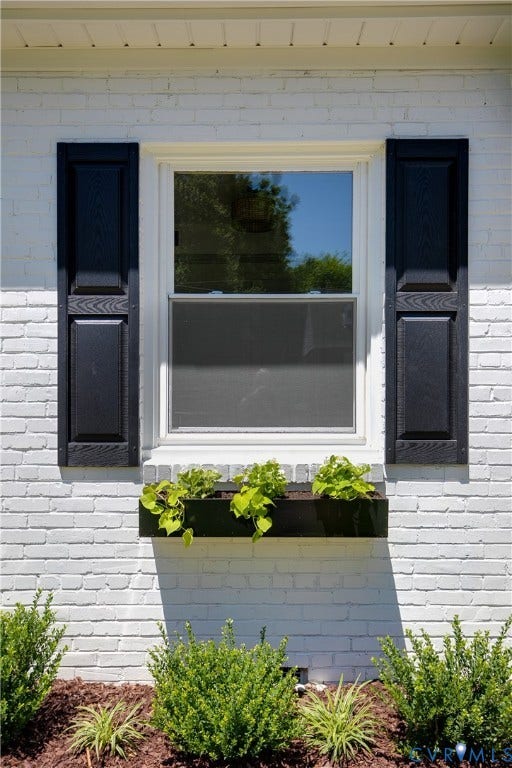 7263 Grace Lane, Mechanicsville, VA 23111 White painted brick exterior featuring a double-hung window with white framing, black louvered shutters, and a black window box with plantings