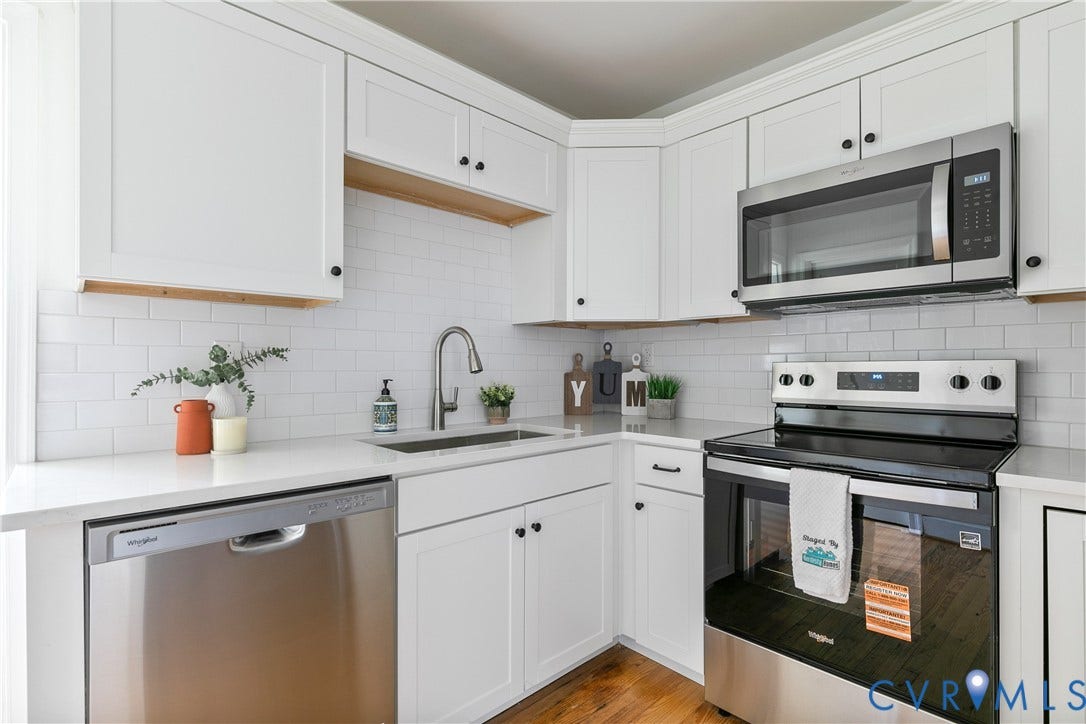 7263 Grace Lane, Mechanicsville, VA 23111 Modern kitchen featuring white shaker cabinetry, stainless steel appliances, a subway tile backsplash, light countertops, and wood-finish flooring