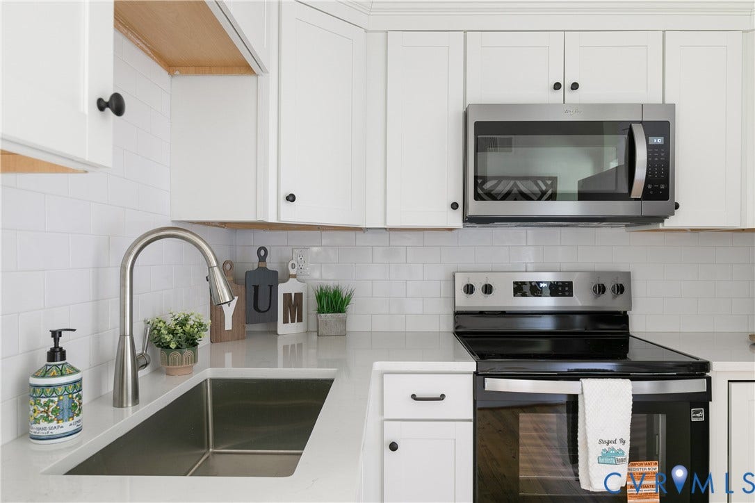 7263 Grace Lane, Mechanicsville, VA 23111 Modern kitchen featuring white shaker cabinetry with dark hardware, stainless steel appliances, a subway tile backsplash, a gooseneck faucet, and light-toned countertops