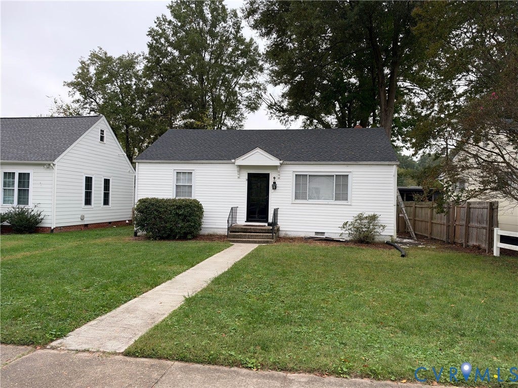 6523 Stuart Avenue, Richmond, VA 23226 Single-story residence featuring white horizontal siding, a pitched roof with asphalt shingles, a central front entry with a protective hood, and a concrete walkway