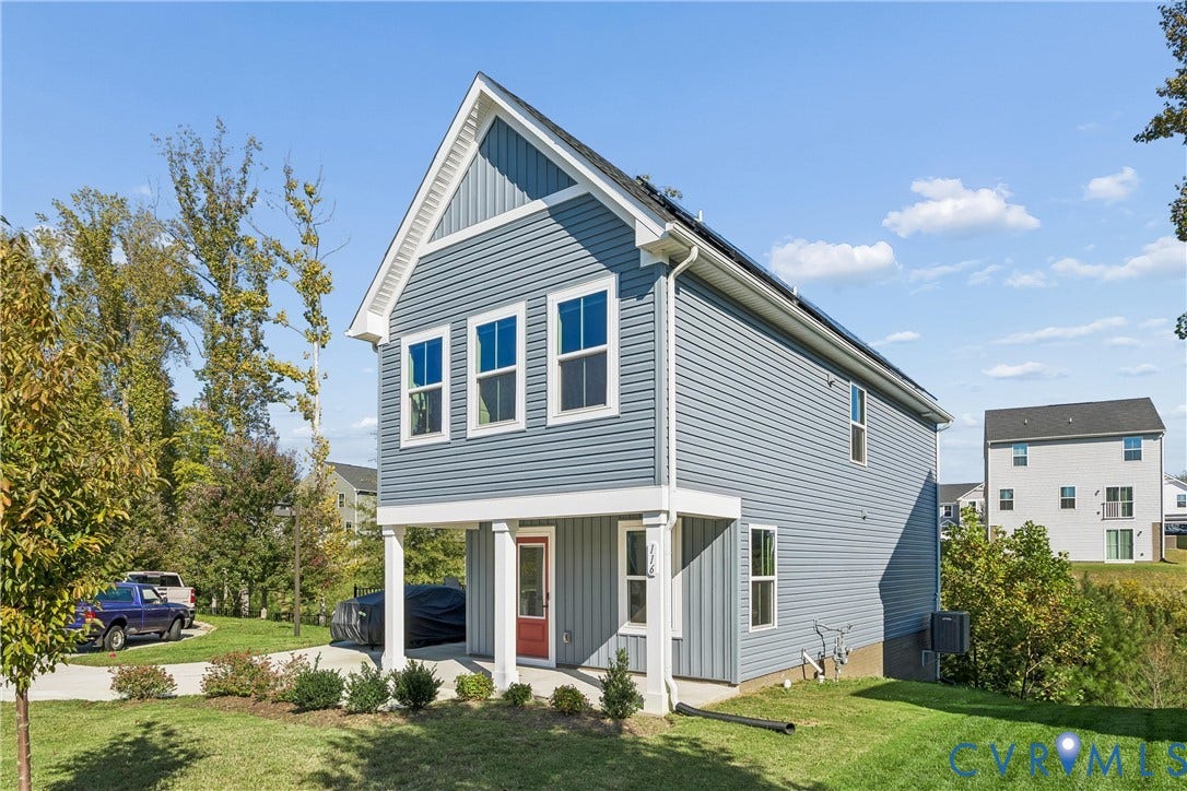 Two-story home with blue horizontal and vertical siding, a covered front porch with square columns, and solar panels installed on the roof