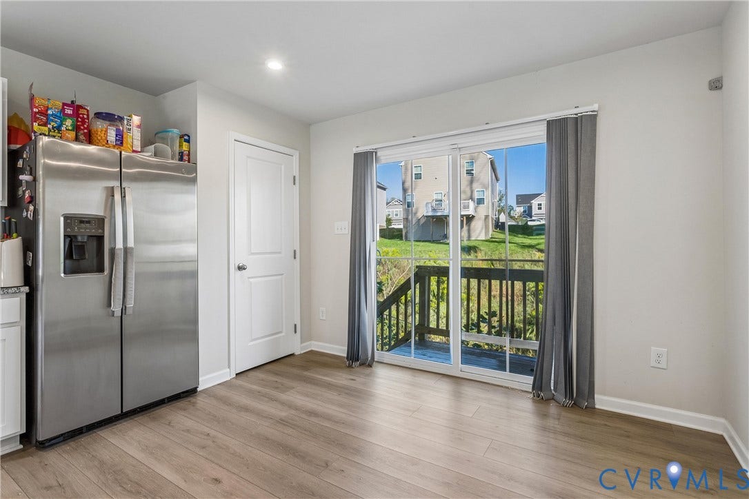 Wood-finish flooring, stainless steel side-by-side refrigerator, recessed lighting, and sliding glass doors with exterior deck access