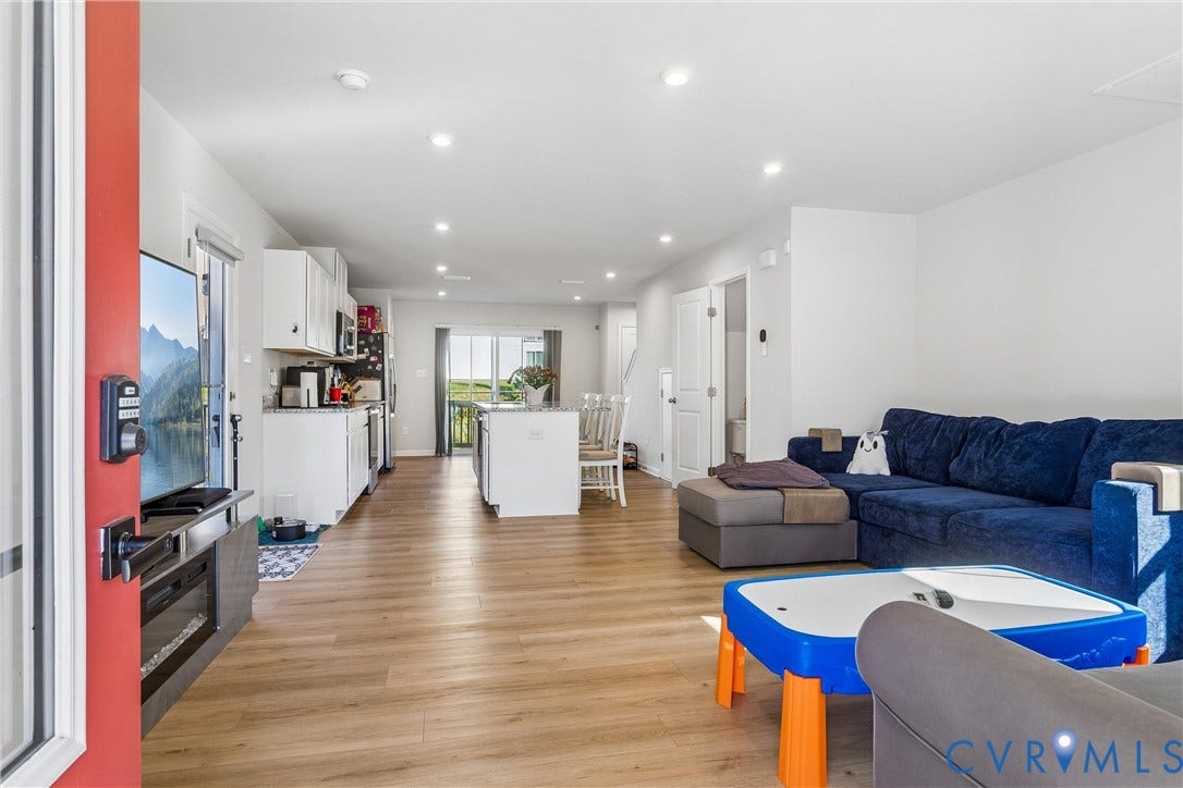Open-concept interior featuring wood-finish flooring, recessed lighting, white cabinetry, and a central kitchen island