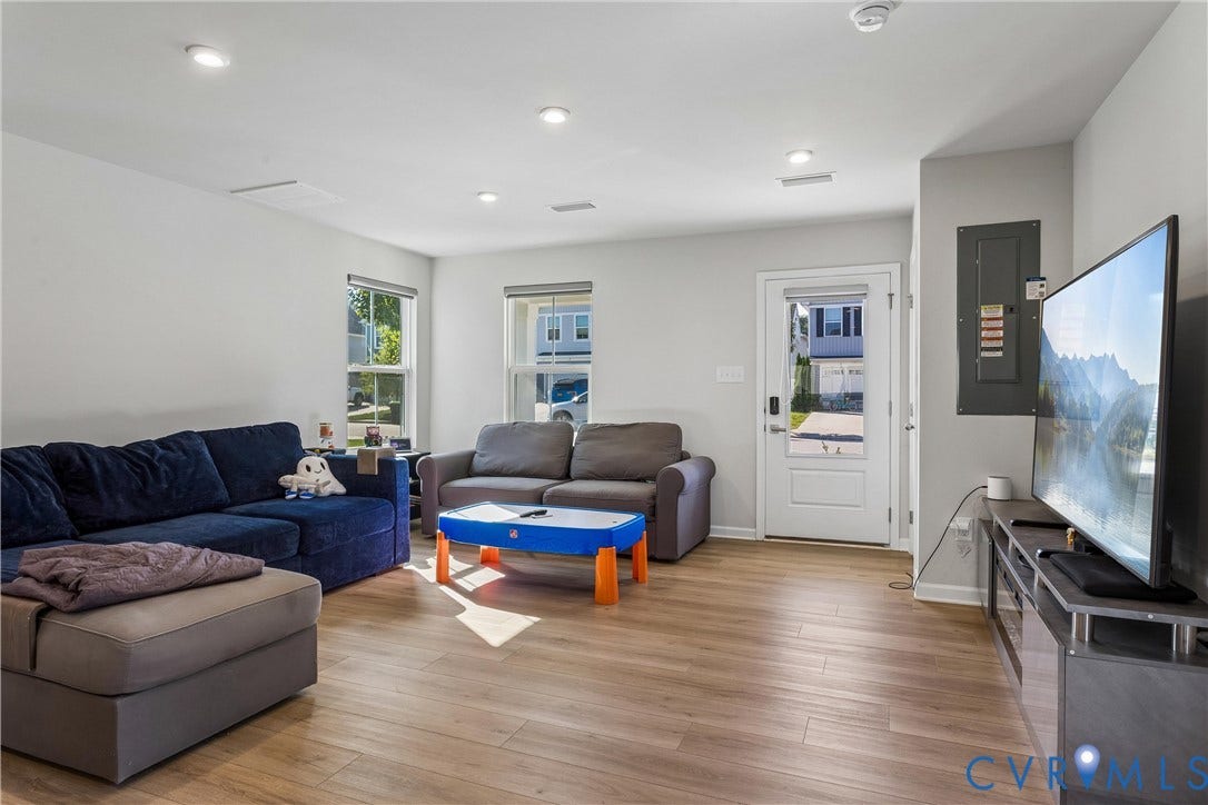 Living area featuring wood-finish flooring, recessed lighting, and a glass-paneled exterior door