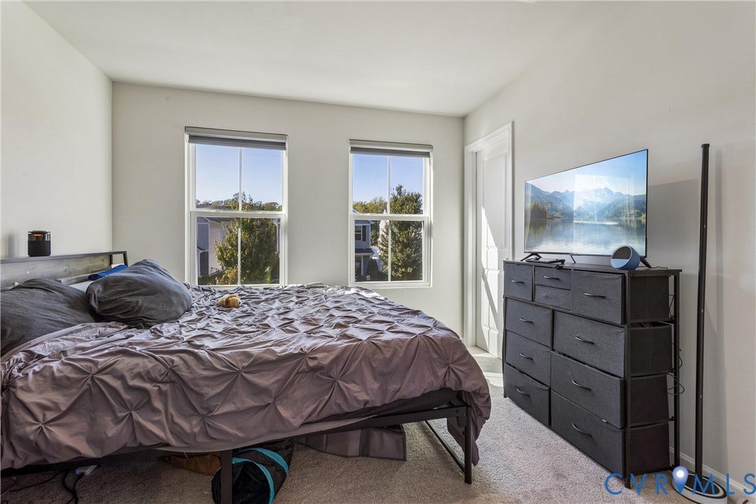 Bedroom featuring neutral wall paint, wall-to-wall carpeting, and two double-hung windows with retractable shades