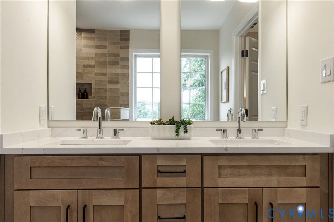 8060 Pebblepath Parkway, Hanover, VA 23111 Double vanity featuring wood-finish cabinetry, rectangular under-mount sinks, a solid-surface countertop, and polished chrome widespread faucets