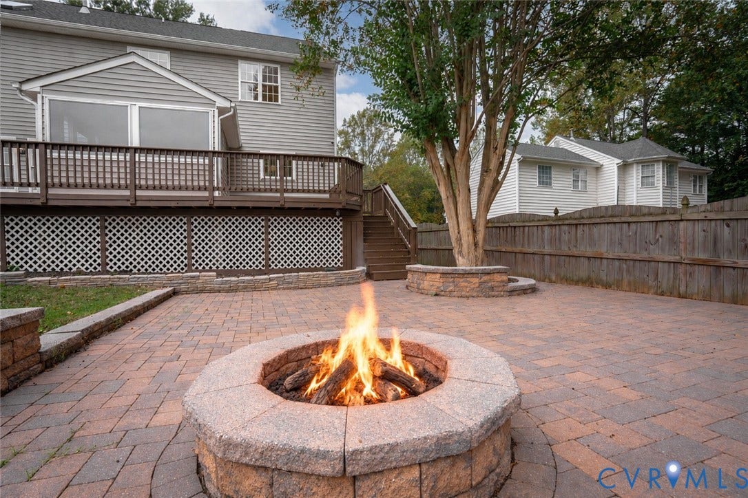 8060 Pebblepath Parkway, Hanover, VA 23111 Paver patio featuring a circular stone fire pit, tiered wooden deck with lattice skirting, and stone retaining walls