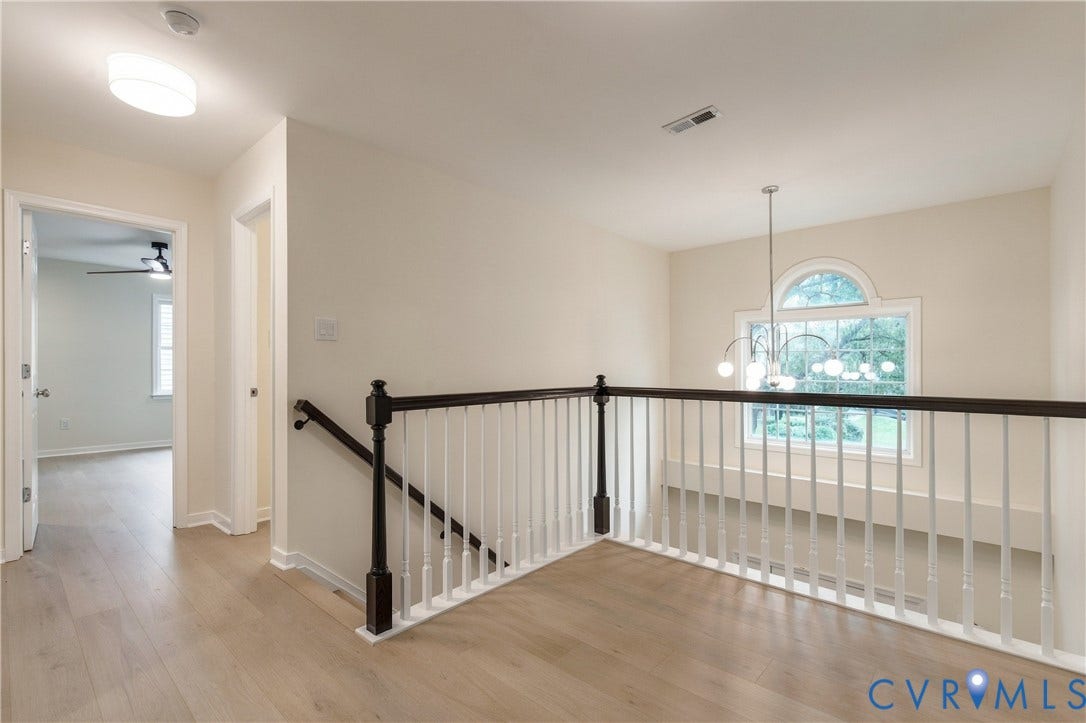 8060 Pebblepath Parkway, Hanover, VA 23111 Landing area featuring wood-finish flooring, a decorative arched window, a multi-arm chandelier, and a staircase with white balusters and dark wood-finish handrails