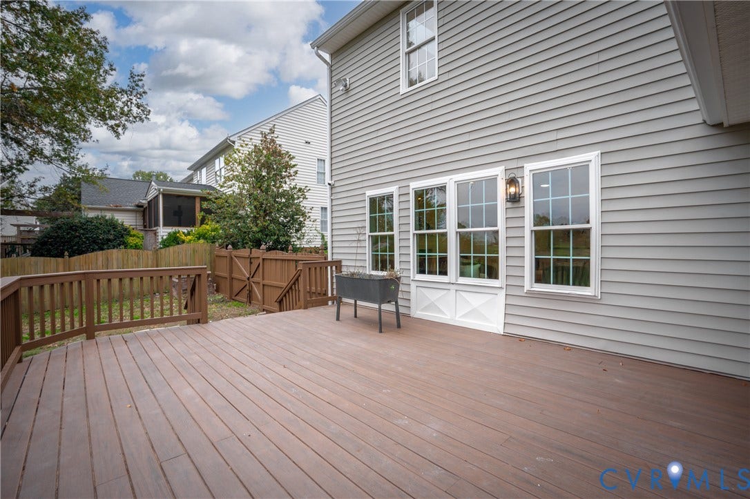 8060 Pebblepath Parkway, Hanover, VA 23111 Spacious rear deck featuring horizontal composite decking, wood-finish railing, light-grey siding, multi-pane windows, and a wood privacy fence