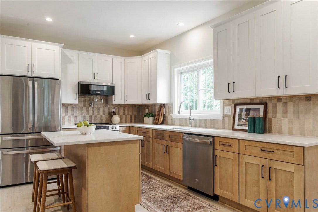 8060 Pebblepath Parkway, Hanover, VA 23111 Kitchen featuring white upper cabinetry, natural wood-finish lower cabinetry, stone-tile backsplash, stainless steel appliances, and a central island with a solid surface countertop