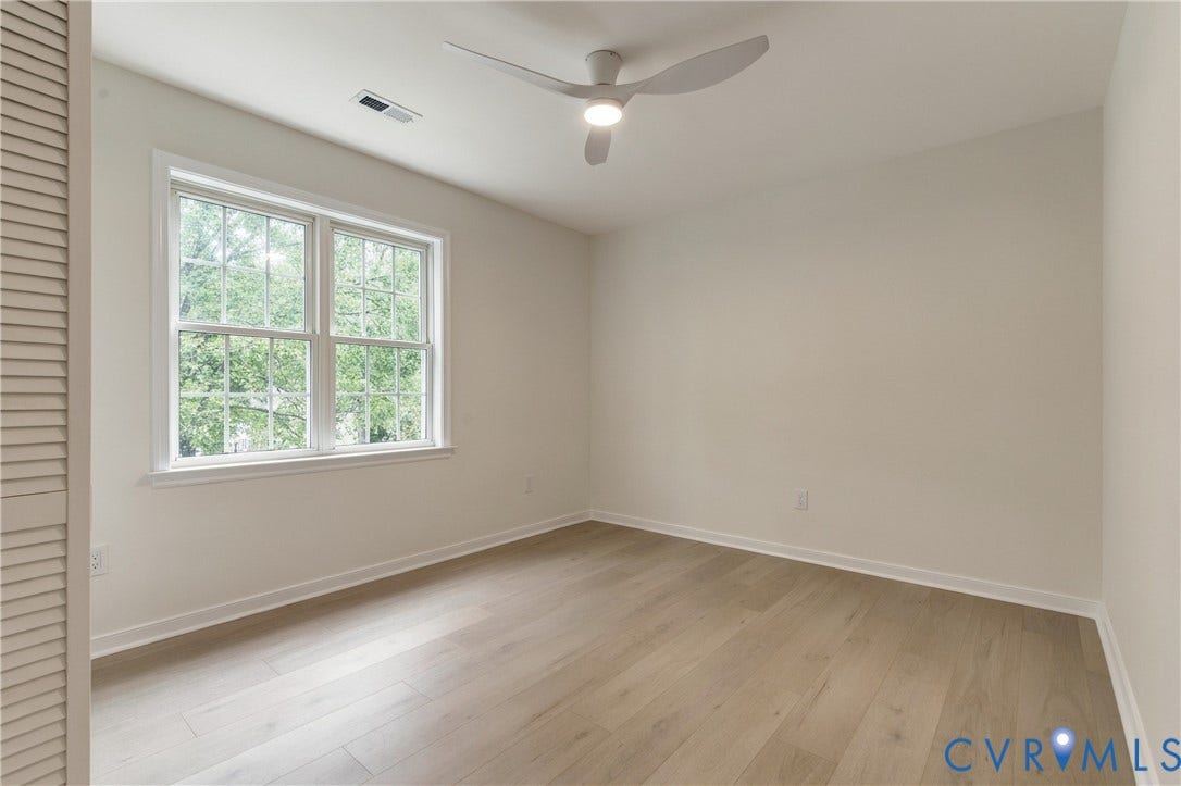 8060 Pebblepath Parkway, Hanover, VA 23111 Neutral-toned interior featuring wood-finish flooring, a multi-pane window, louvered closet door, and a modern three-blade ceiling fan with integrated lighting