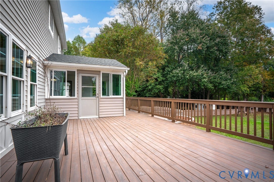 8060 Pebblepath Parkway, Hanover, VA 23111 Expansive wood-finish deck featuring a full-width railing, light-filled sunroom addition, exterior wall-mounted lighting, and siding exterior