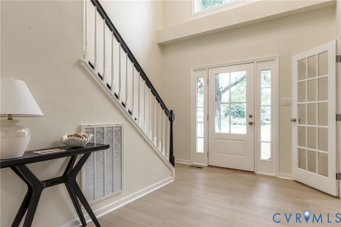 8060 Pebblepath Parkway, Hanover, VA 23111 Foyer featuring high ceilings, wood-finish flooring, a staircase with a black handrail and white balusters, a multi-pane glass entry door with side lights, and a French-style glass pane door