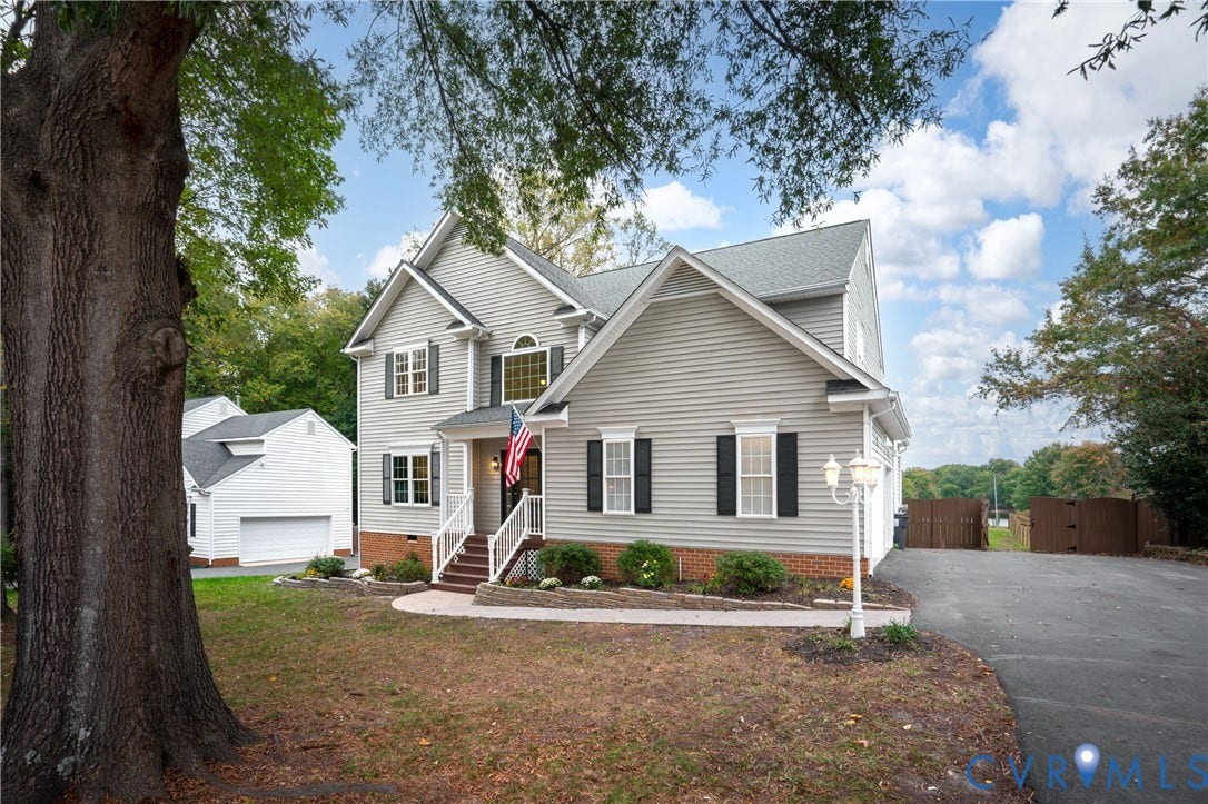 8060 Pebblepath Parkway, Hanover, VA 23111 Two-story home with gray horizontal siding, brick foundation accents, covered entryway, asphalt shingle roof, and detached garage