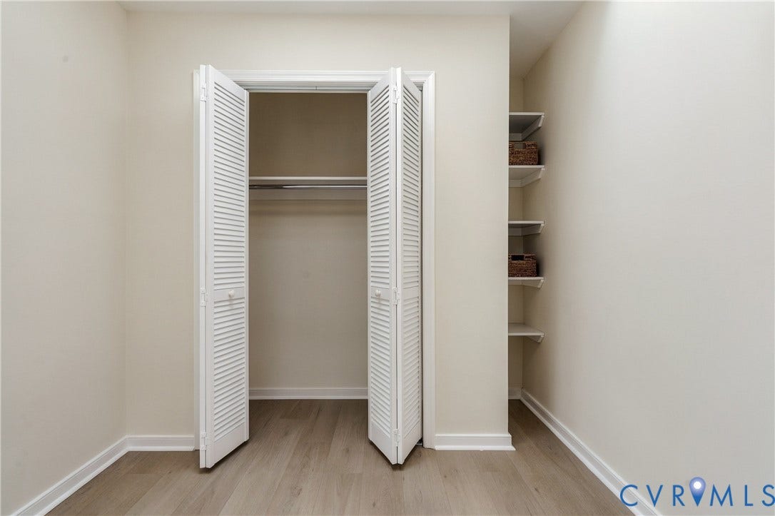 8060 Pebblepath Parkway, Hanover, VA 23111 Closet featuring white louvered bifold doors, integrated hanging rod, wood-finish flooring, and built-in wall shelving
