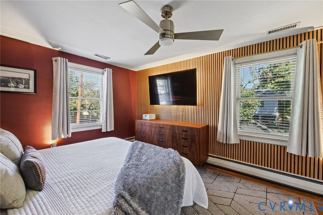 1009 Malvern Avenue, Malvern Gardens, Richmond, VA 23221 Bedroom featuring an accent wall with vertical wood slat paneling, dual windows with blinds, and a brushed nickel ceiling fan with integrated lighting