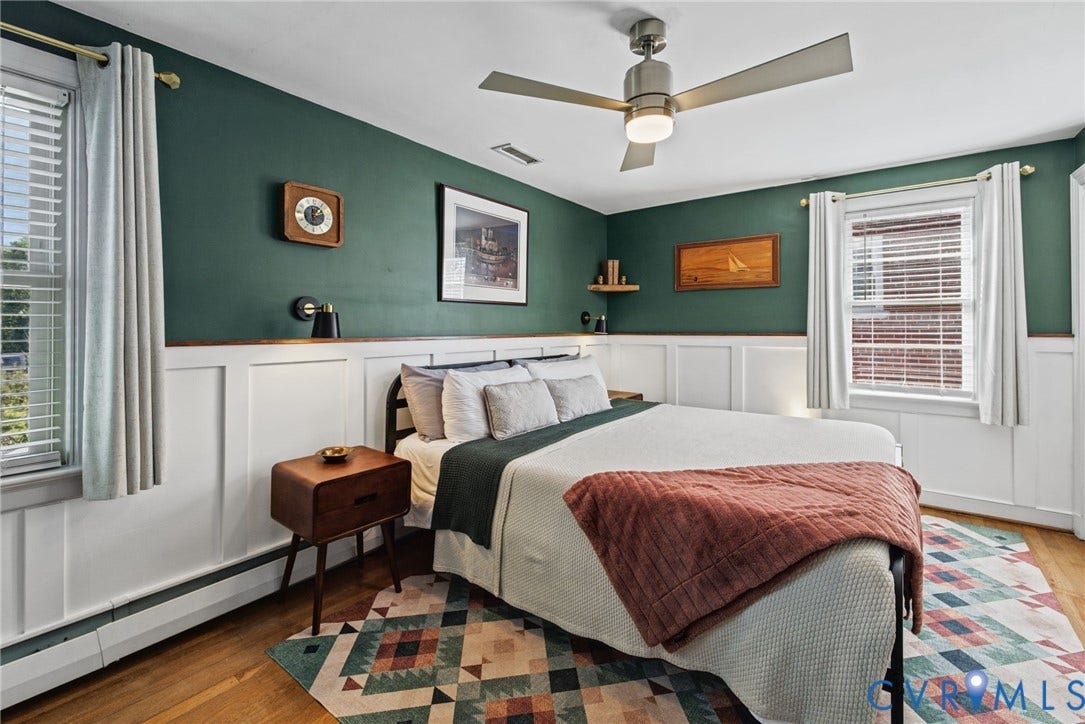 1009 Malvern Avenue, Malvern Gardens, Richmond, VA 23221 Bedroom featuring white wainscoting, matte dark green wall finish, wood-finish flooring, brushed nickel ceiling fan with integrated lighting, and dual windows