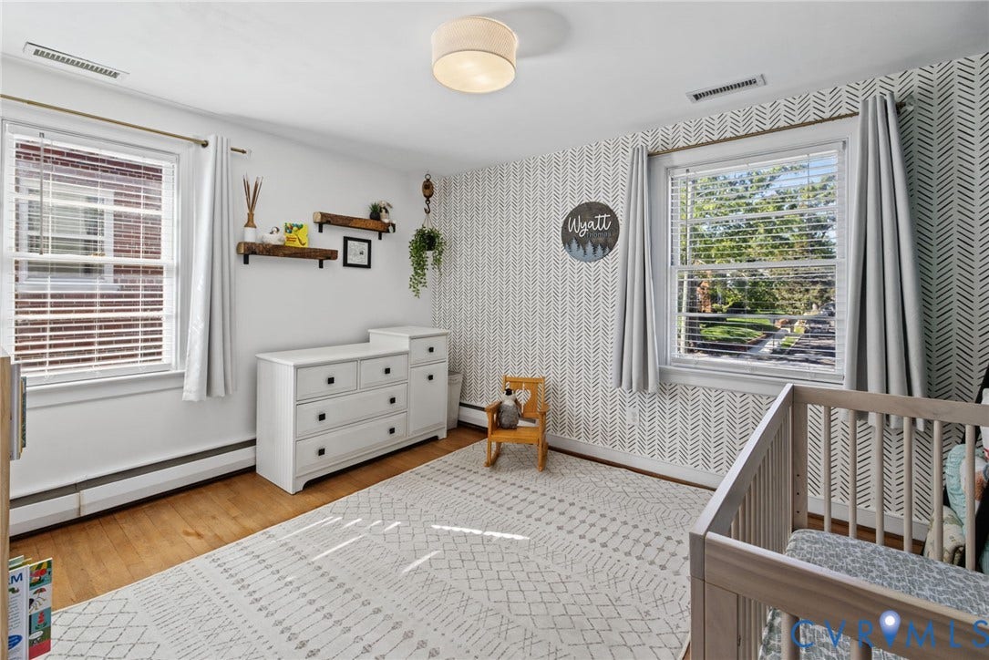 1009 Malvern Avenue, Malvern Gardens, Richmond, VA 23221 Bedroom featuring wood-finish flooring, dual windows with decorative trim, a geometric-patterned accent wall, and a flush-mount drum light fixture
