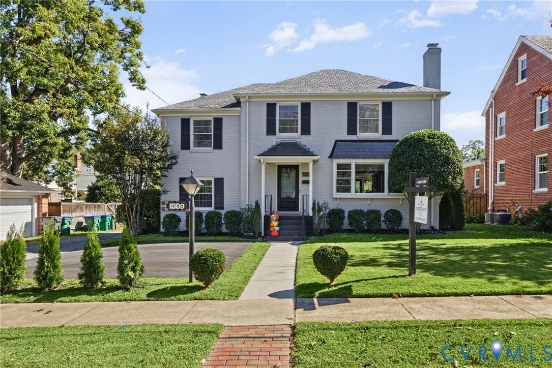 1009 Malvern Avenue, Malvern Gardens, Richmond, VA 23221 Two-story residence featuring a painted brick exterior, dark window shutters, a prominent chimney, a covered front entryway, and an asphalt driveway