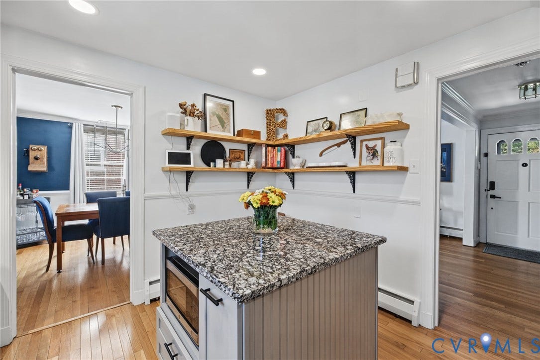 1009 Malvern Avenue, Malvern Gardens, Richmond, VA 23221 Kitchen island featuring stone-finish countertop, built-in microwave, and beadboard cabinetry, complemented by mounted natural wood shelving and wood-finish flooring