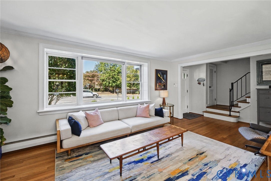 1009 Malvern Avenue, Malvern Gardens, Richmond, VA 23221 Living area featuring large multi-pane windows, wood-finish flooring, crown molding, and a staircase with a black metal railing