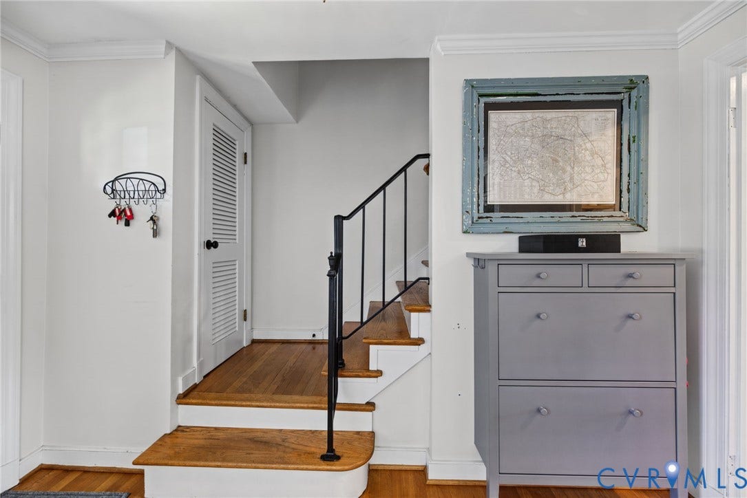 1009 Malvern Avenue, Malvern Gardens, Richmond, VA 23221 Staircase featuring wood-finish treads, white risers, and a black wrought-iron handrail, accented by crown molding and a louvered closet door