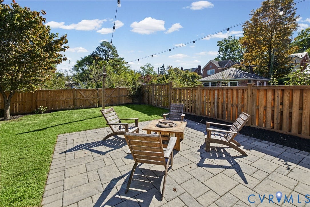 1009 Malvern Avenue, Malvern Gardens, Richmond, VA 23221 Backyard featuring a paved stone patio, manicured lawn, perimeter wood fencing, and overhead string lighting