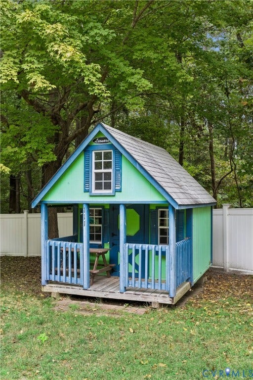Custom outdoor structure featuring a pitched roof, front porch with decorative balusters, paneled siding, and multiple windows