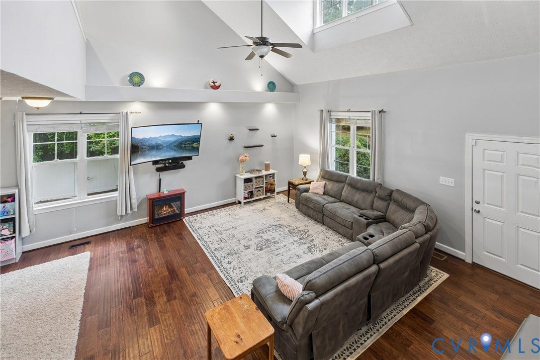 Vaulted ceilings featuring a skylight, wood-finish flooring, recessed architectural shelving, and multi-pane windows