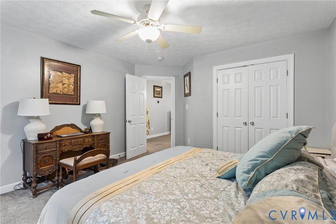 Bedroom featuring neutral wall paint, carpeted flooring, a ceiling fan with integrated lighting, and a double-door reach-in closet