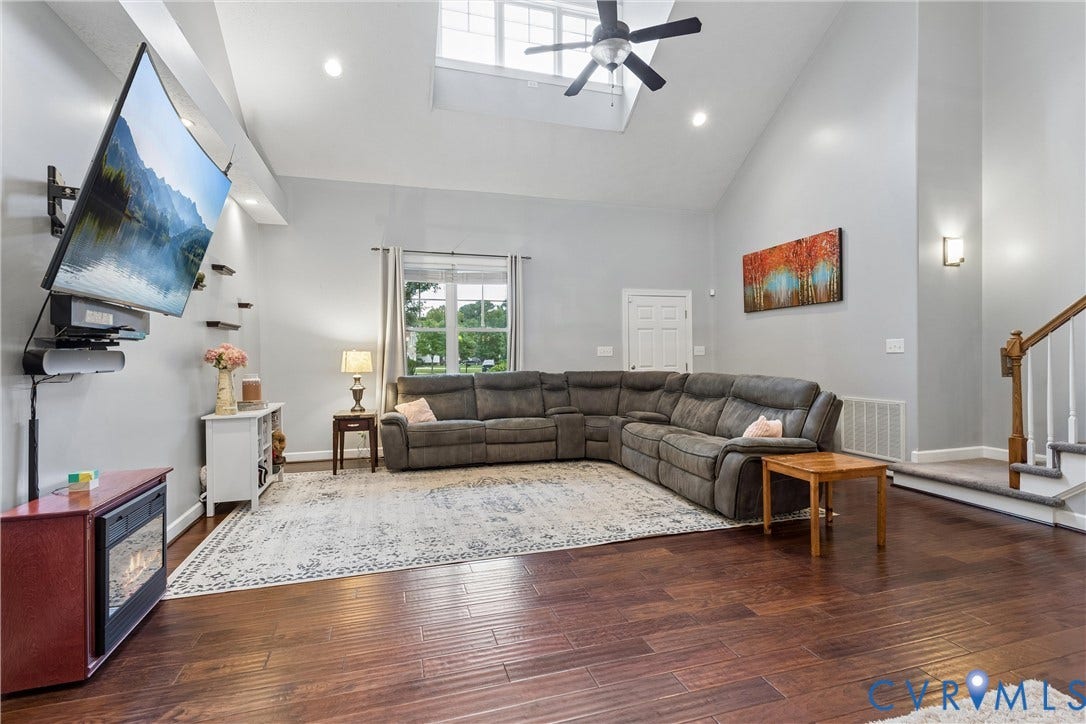 Vaulted ceiling featuring a large skylight, recessed lighting, and a ceiling fan, complemented by wood-finish flooring