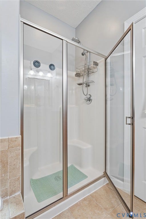 Walk-in shower featuring a white molded surround, built-in bench seating, a chrome handheld shower fixture, and a framed glass enclosure