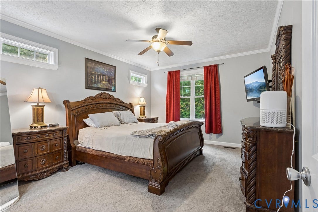 Neutral-toned walls with crown molding, carpeting, and a ceiling-mounted light fixture with a fan