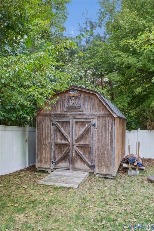 Storage shed with a gambrel roof, double-door entry, exterior wood siding, and an integrated ramp