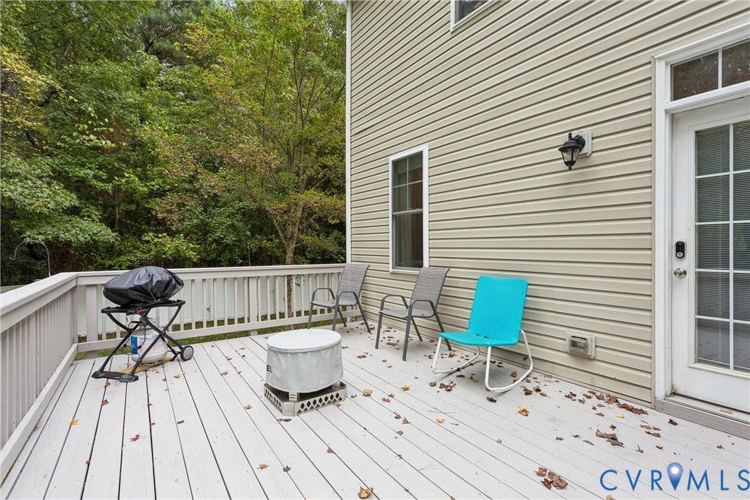 Elevated wood-plank deck featuring light-toned railing, vinyl siding exterior, and exterior wall-mounted lighting