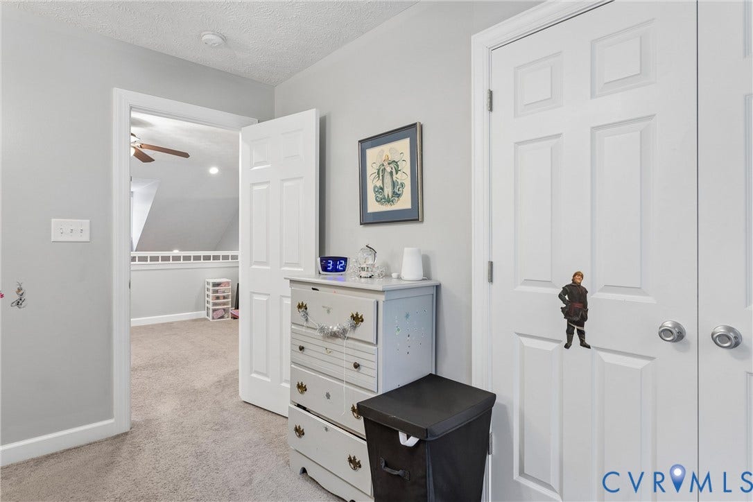 Neutral-toned interior space featuring light grey walls, carpeted flooring, and white multi-panel interior doors