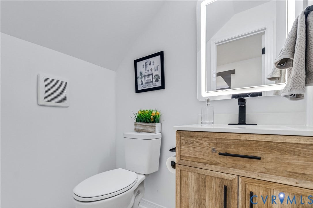 223 S Crater Road, Petersburg, VA 23803 Wood-finish vanity cabinet, solid surface countertop, matte black faucet, and rectangular LED-backlit mirror