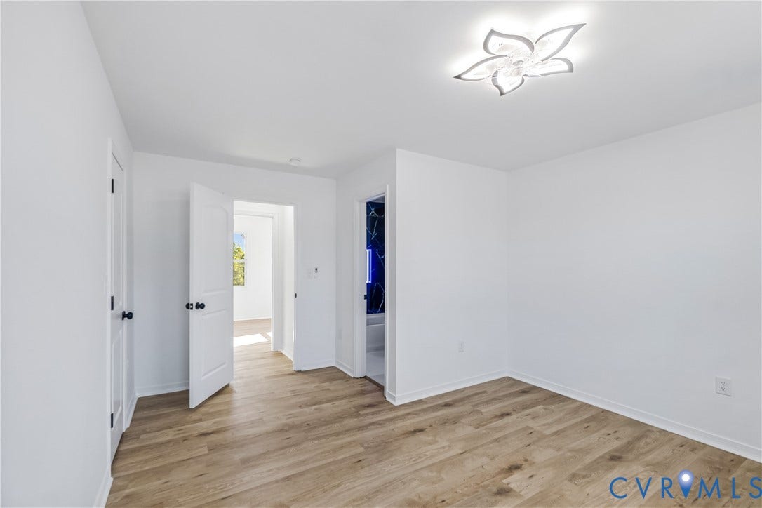 223 S Crater Road, Petersburg, VA 23803 Interior space featuring wood-finish flooring, white walls, and a decorative floral-inspired flush-mount ceiling light fixture