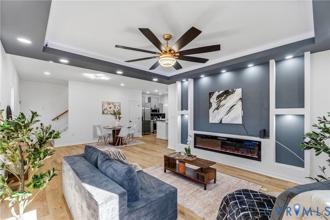 223 S Crater Road, Petersburg, VA 23803 Tray ceiling with recessed lighting, integrated accent wall with built-in shelving, linear electric fireplace, and wood-finish flooring