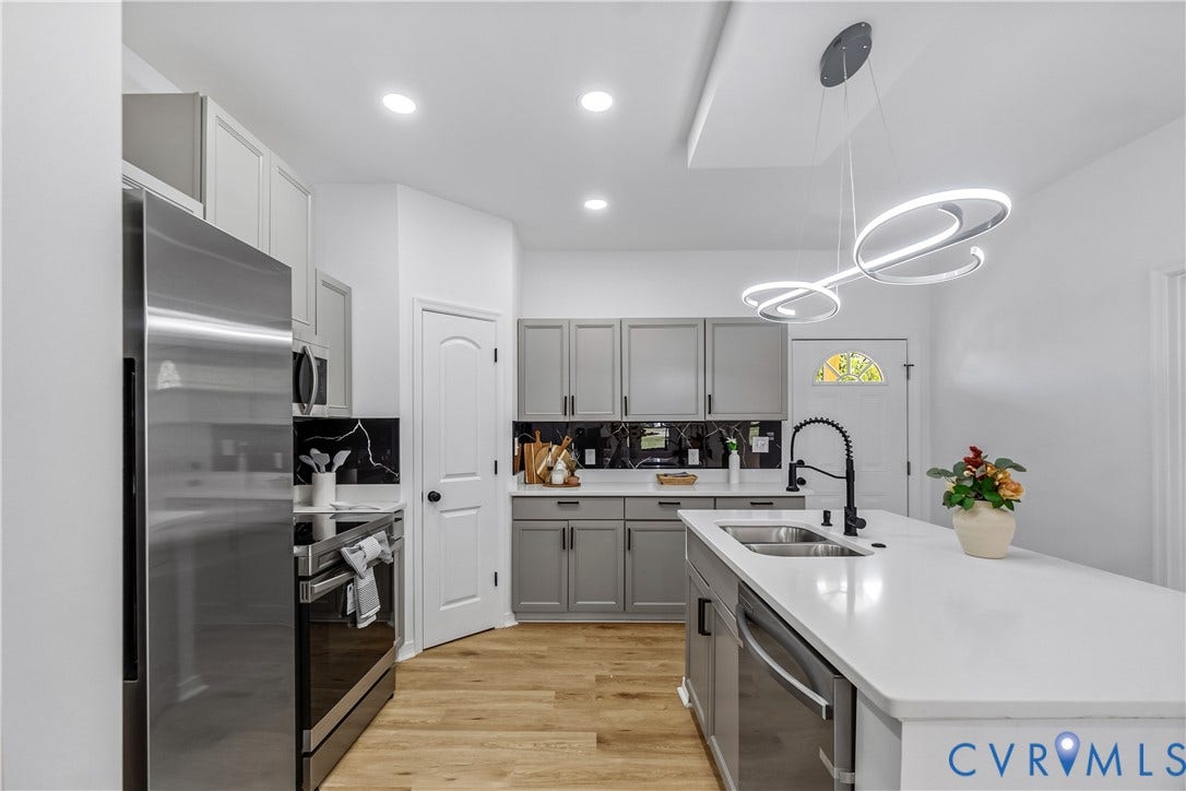 223 S Crater Road, Petersburg, VA 23803 Kitchen featuring grey shaker-style cabinetry, quartz countertops, a central island with a double-basin sink, stainless steel appliances, and wood-finish flooring