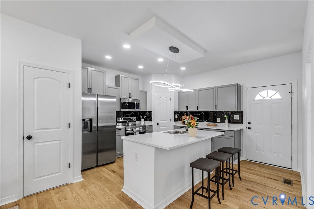 223 S Crater Road, Petersburg, VA 23803 Kitchen featuring gray cabinetry, a white center island with integrated sink, stone-finish countertops, black tile backsplash, and wood-finish flooring
