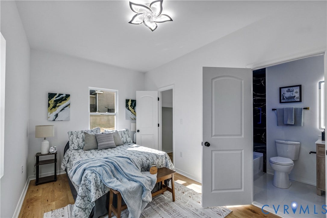 223 S Crater Road, Petersburg, VA 23803 Wood-finish flooring, decorative floral-style ceiling light fixture, and arched-panel interior doors, with an entryway into a bathroom featuring high-contrast tiling