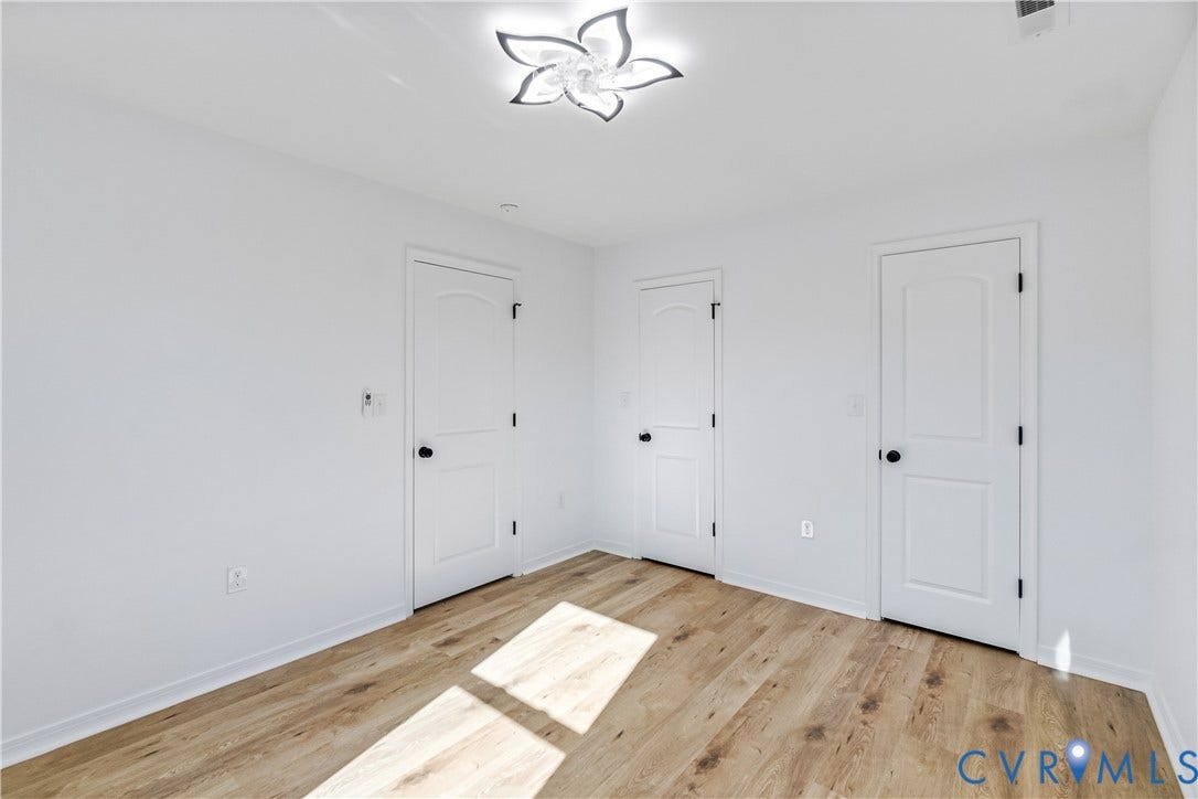 223 S Crater Road, Petersburg, VA 23803 Wood-finish flooring, three-panel interior doors with matte black hardware, and a contemporary petal-style flush-mount ceiling fixture